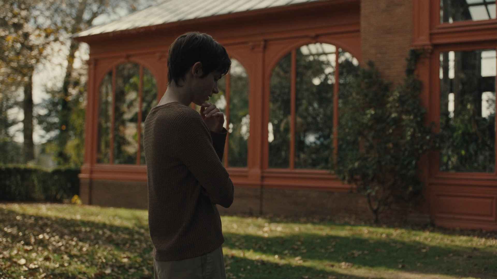 Modern home exterior featuring a luxury orangery extension with a glass roof lantern and large windows and person seeing and thinking.