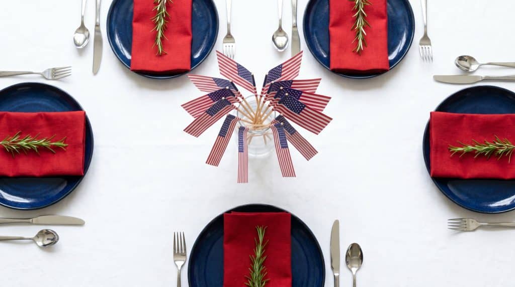 A red, white, and blue Memorial Day table setting with flags and rosemary.