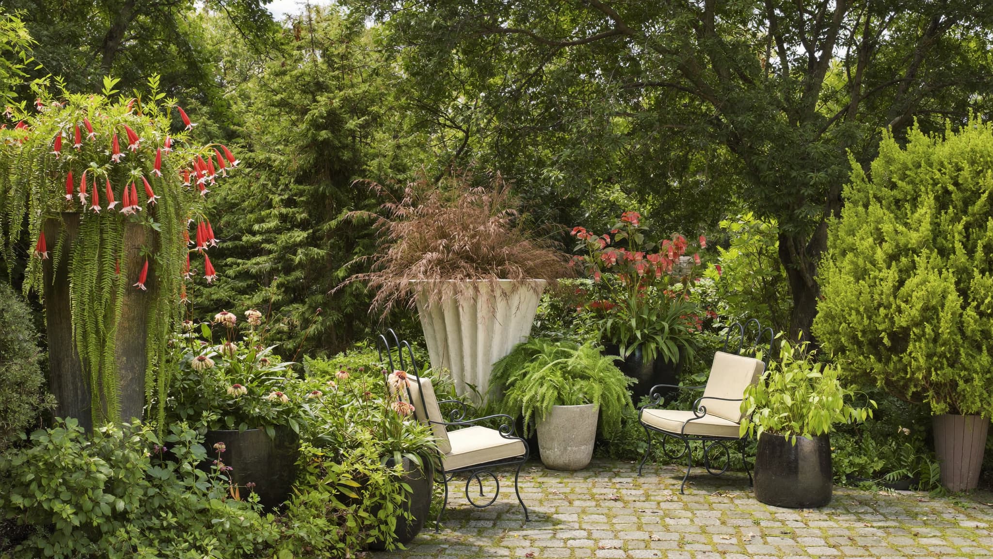 Lush garden patio with potted plants, outdoor seating, and a peaceful green landscape.