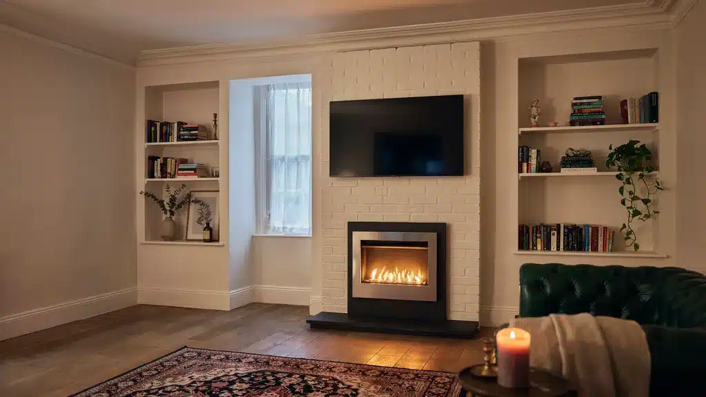 Electric fire and TV stacked in a Victorian chimney breast alcove with built-in shelving in a home