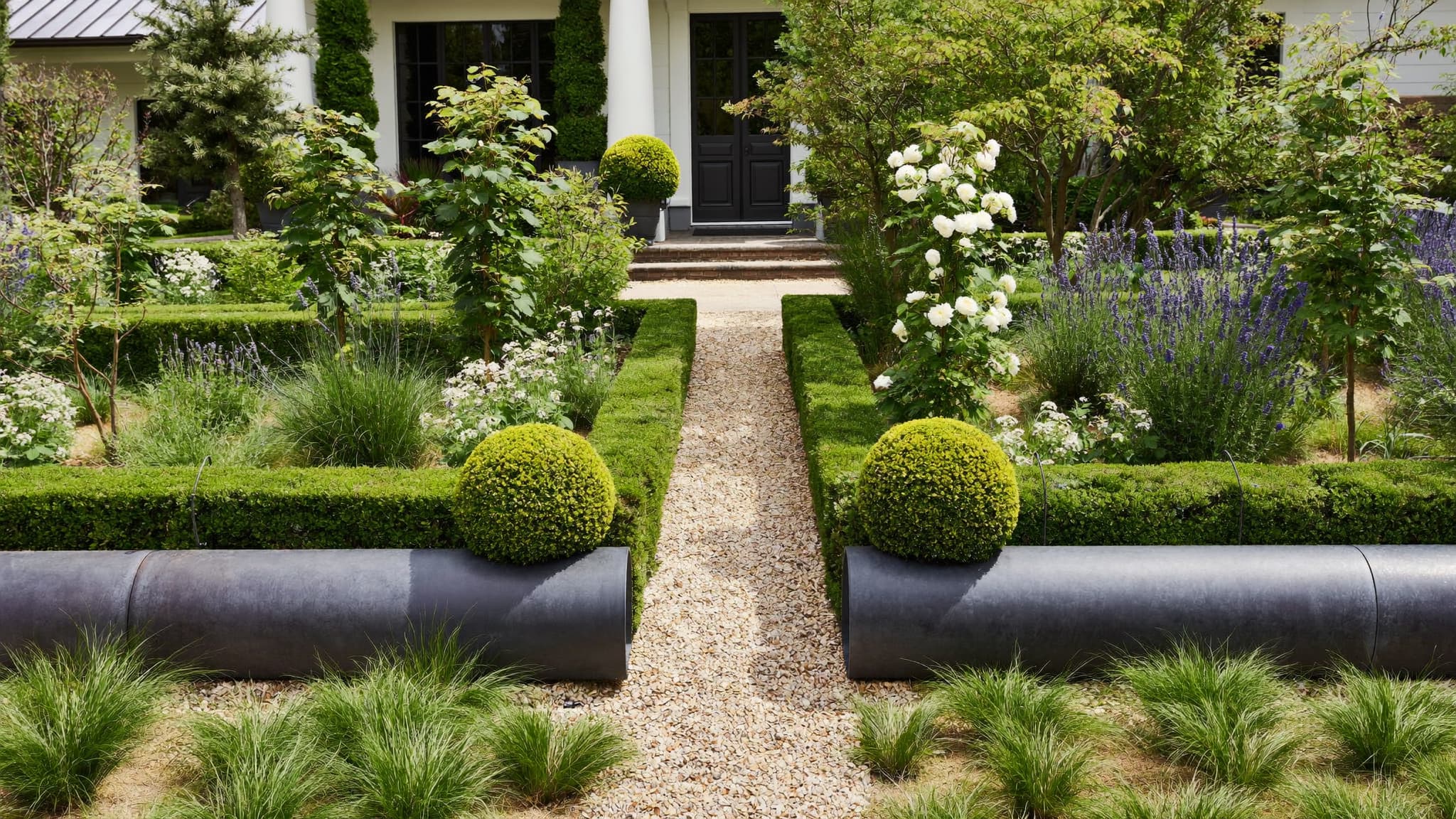 Modern front yard garden with gravel path, trimmed shrubs, and lush green landscaping.