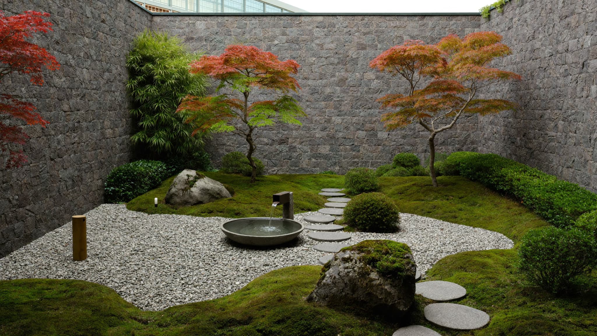 Minimalist Japanese zen garden with raked gravel, stone pathway, moss, and small maple trees.