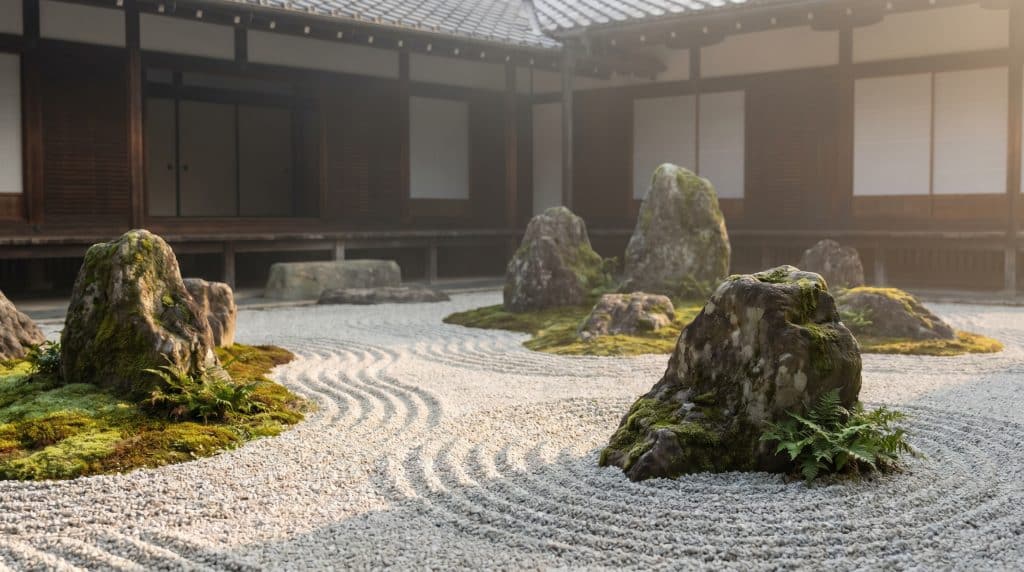 Serene Japanese Zen rock garden with raked gravel patterns, moss-covered stones, and traditional wooden temple architecture