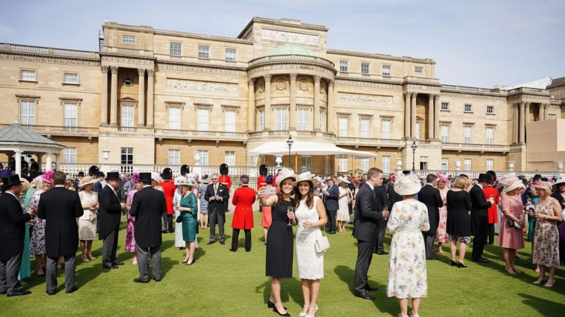 Formally dressed guests gathered on the Buckingham Palace lawn with the historic palace behind them.