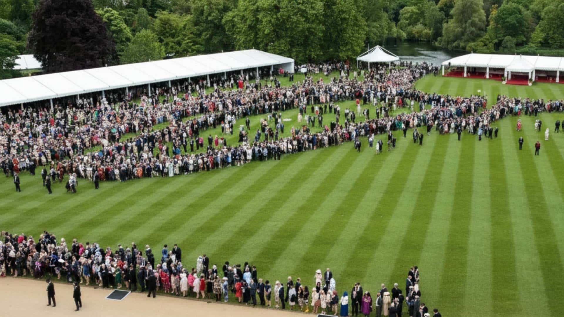 High-angle view of a large crowd of formally dressed guests on a striped lawn at a garden party.