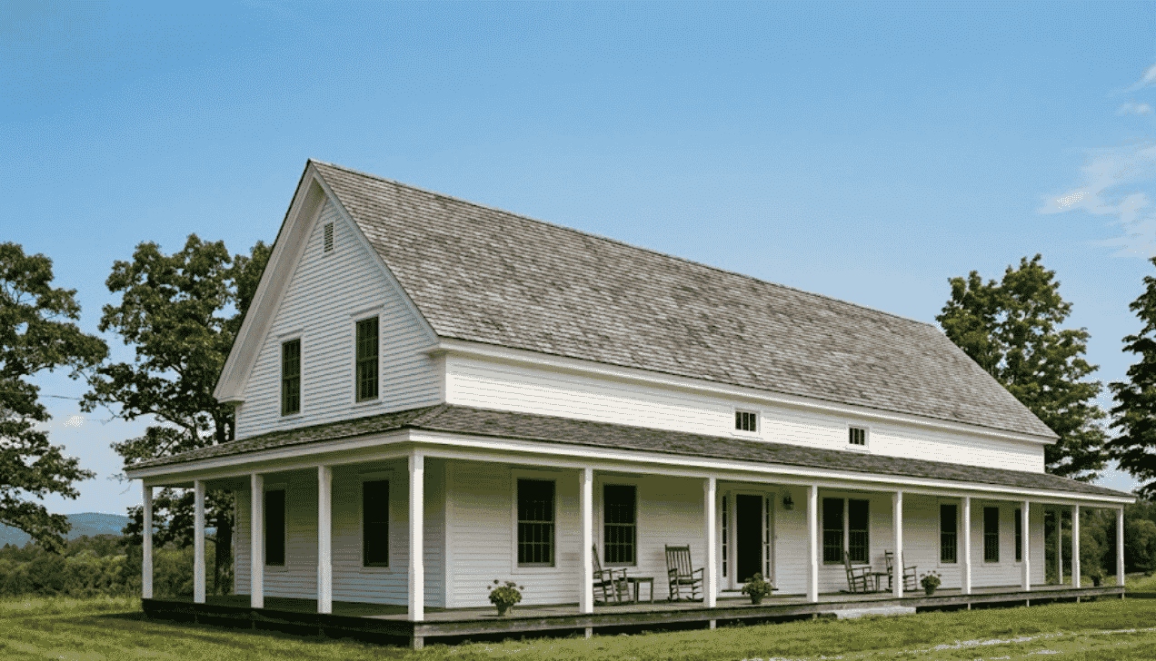 Two-story white farmhouse featuring a long side gable roof and a wrap-around front porch.