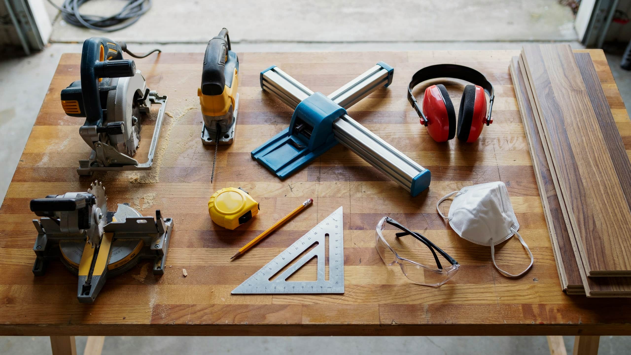 Laminate flooring cutting tools including saws, measuring tape, and safety gear