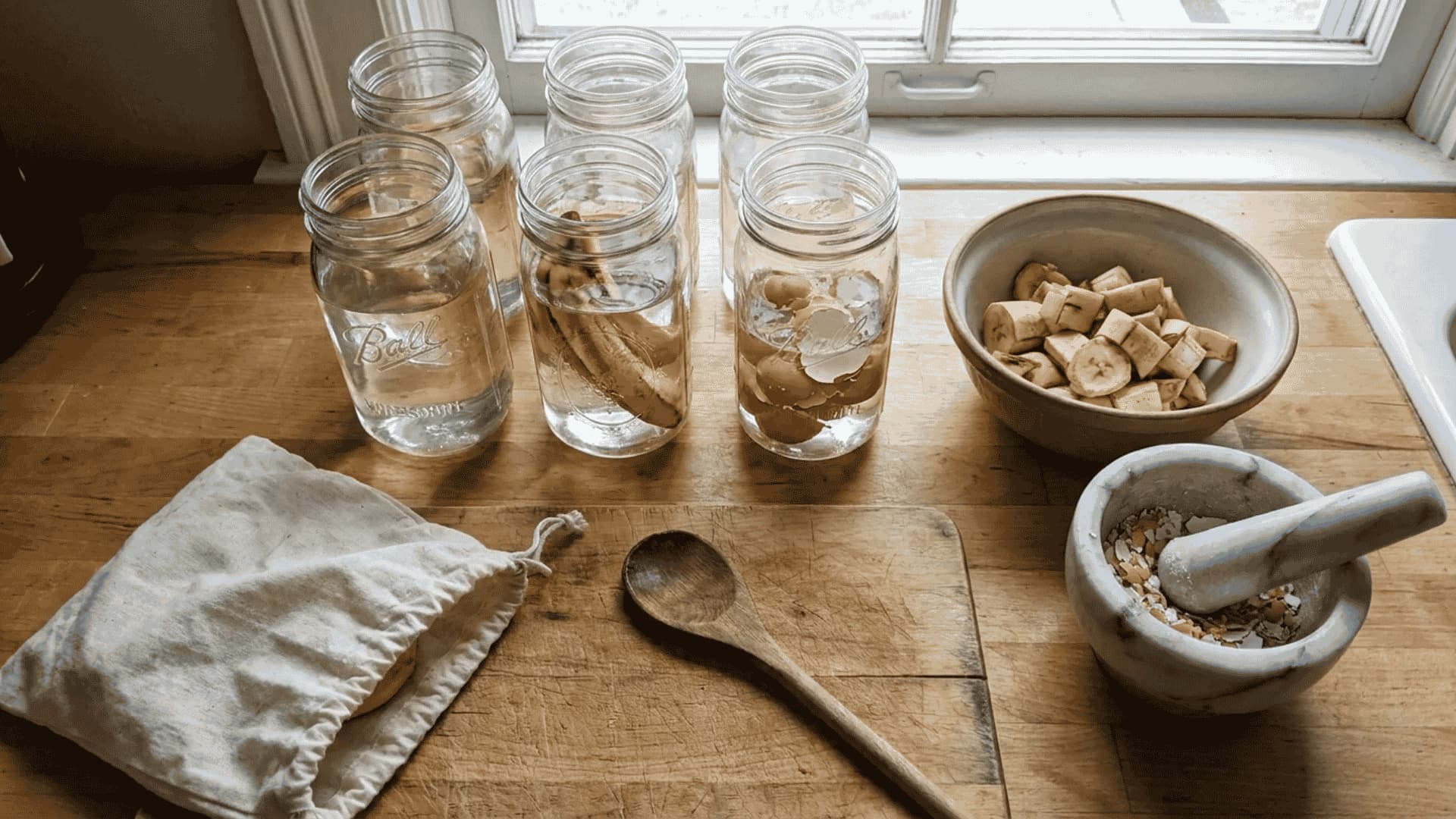 Homemade natural fertilizer ingredients including banana peels, eggshells, and organic kitchen scraps prepared in glass jars on a wooden kitchen counter for plant feeding.