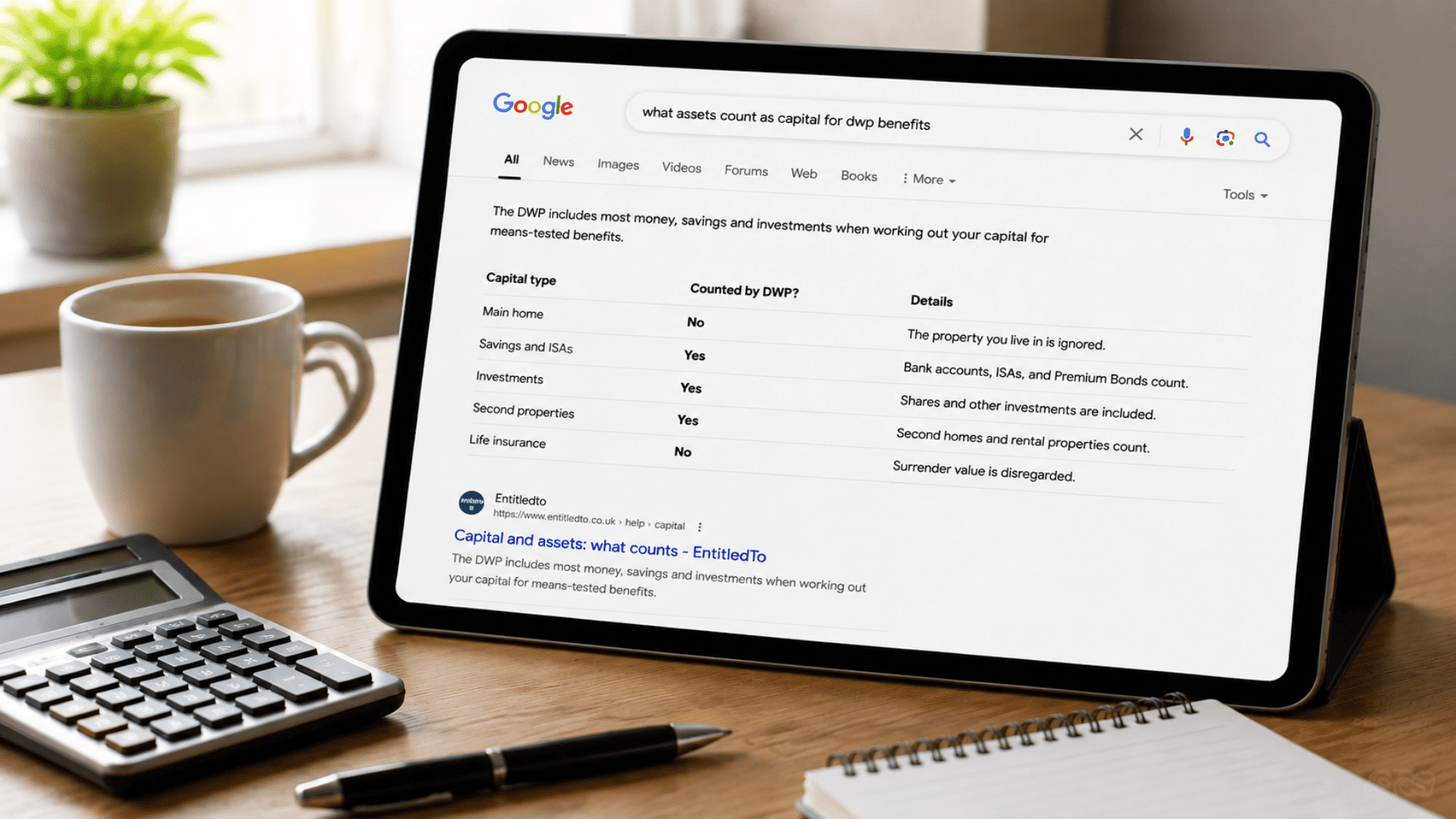 Tablet showing Google search results about DWP capital assets, with calculator, coffee mug, pen, and notebook on a home office desk.