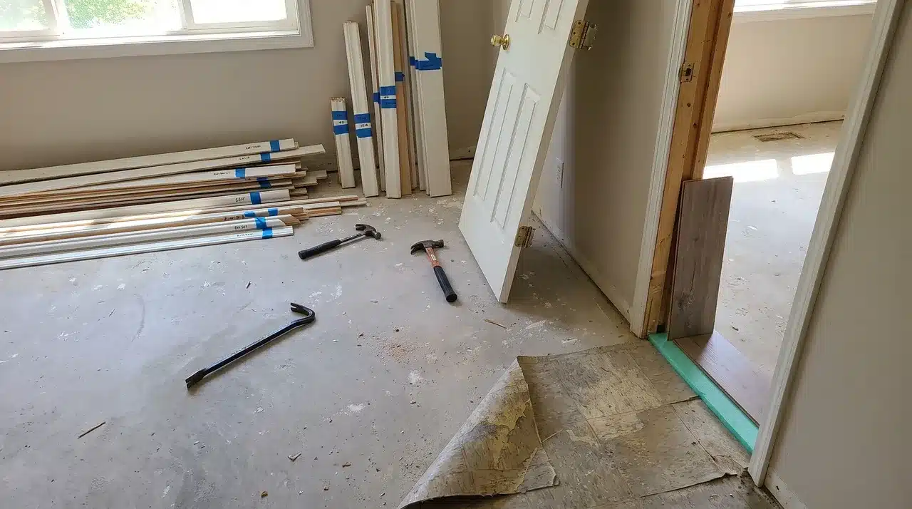 Removed door trim, stacked molding, and tools to prepare a room for new flooring installation.